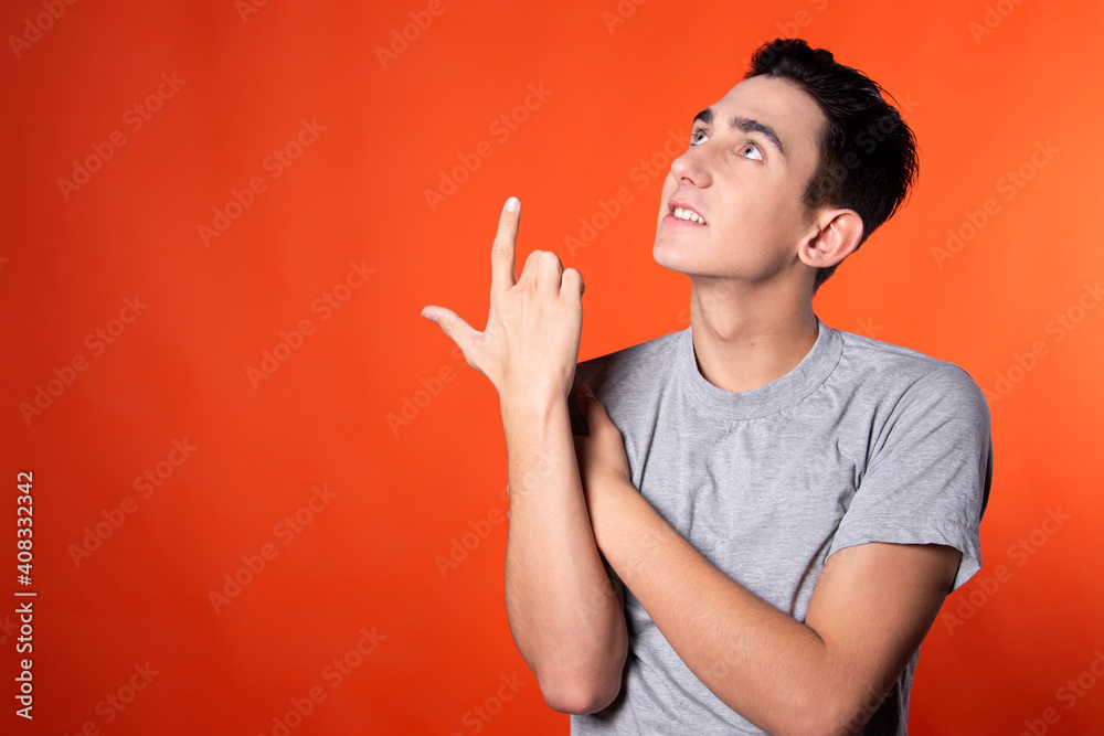 The young man is actively gesturing. Expression of emotions. Blue clothes. Orange background. Point of view. The young man is actively gesturing. Expression of emotions. Blue clothes. Orange background. Point of view.