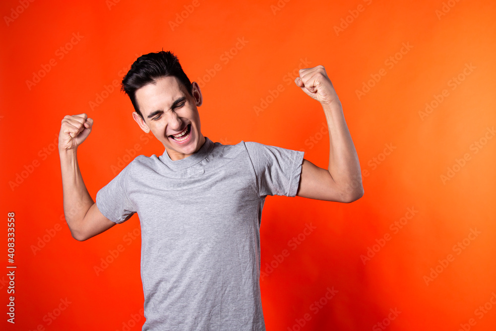 The young guy is happy about the victory. Feelings and emotions. Orange background. The young guy is happy about the victory. Feelings and emotions. Orange background.