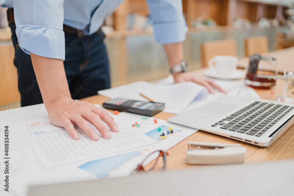 Businessman stand up and reading paper graph and checking document data calculator for calculate budget accountancy. finance and accounting concept. Businessman stand up and reading paper graph and checking document data calculator for calculate budget accountancy. finance and accounting concept.