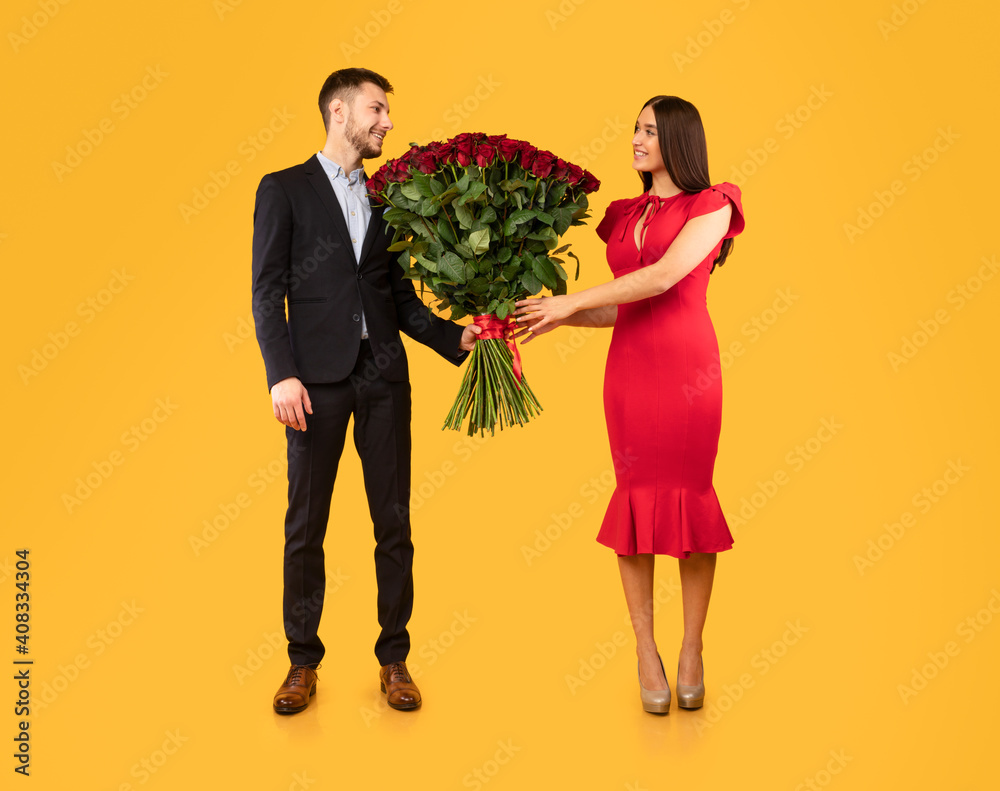 Man Giving Bouquet Of Roses To Woman On Yellow Background Man Giving Bouquet Of Roses To Woman On Yellow Background