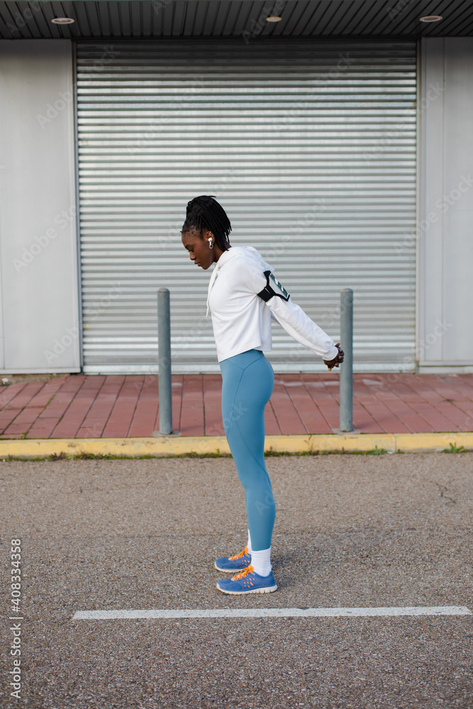 Female urban athlete training outside. Chest and shoulder warm up exercise before running.