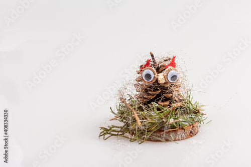 Kiefernzapfen als Eule auf einer Holzscheibe als Weihnachtsdekoration