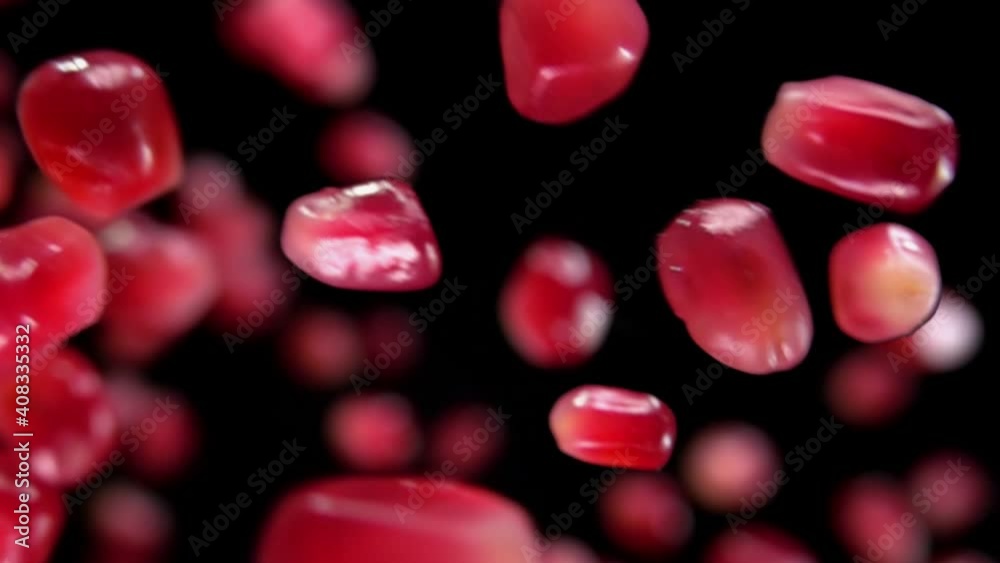 Super close-up of red juicy grains of pomegranate bouncing on the black background in slow motion Super close-up of red juicy grains of pomegranate bouncing on the black background in slow motion