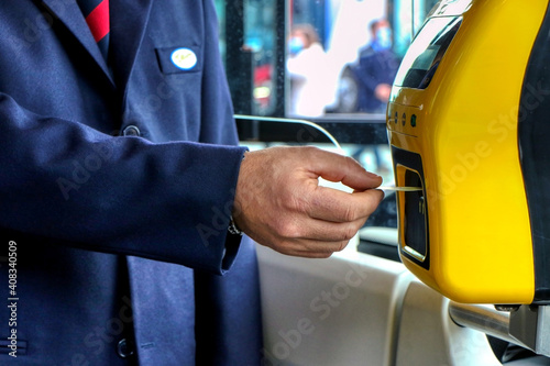 Man hand inserts the bus ticket into the validator, validating and ticking © Massimo Todaro
