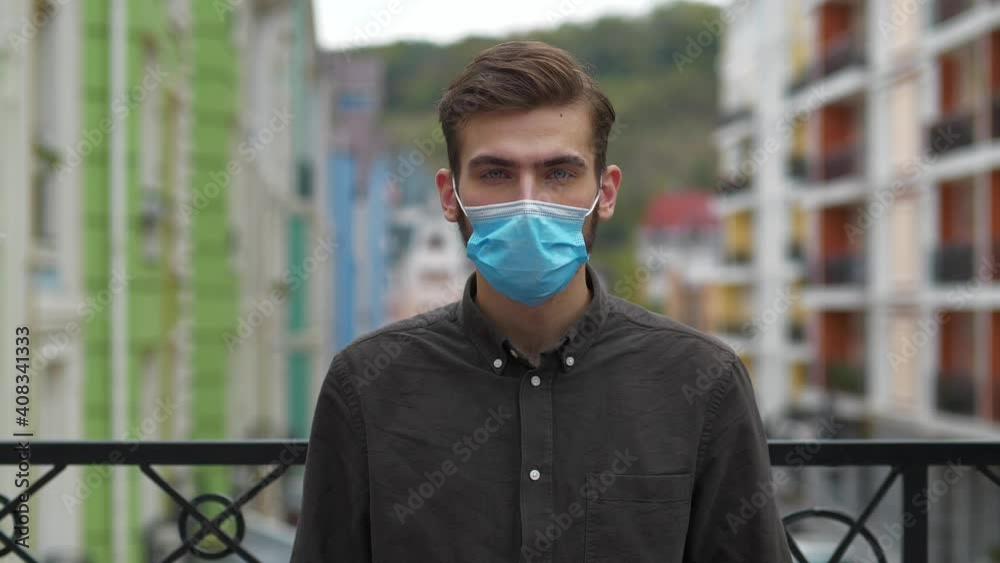 Handsome man in medical protective face mask looks at the camera. Covid concept health and safety, coronavirus quarantine, social distancing, next wave covid virus protection Handsome man in medical protective face mask looks at the camera. Covid concept health and safety, coronavirus quarantine, social distancing, next wave covid virus protection