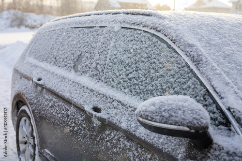 Samochód zasypany śniegiem na parkingu zimową porą, auto przykryte białym puchem śnieżnym © Magdalena