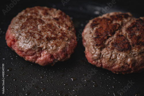 Hamburguesa de carne cruda en sartén negra con aceite