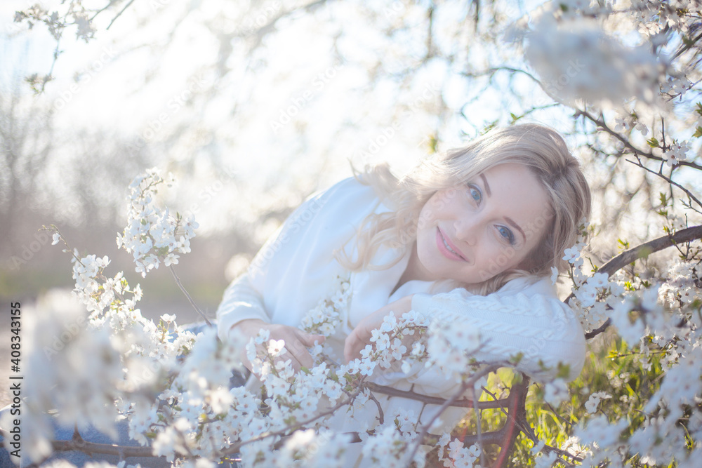 Portrait of pretty blong girl posing against the spring flowers. Woman enjoy the healthy aroma smelling in the garden Portrait of pretty blong girl posing against the spring flowers. Woman enjoy the healthy aroma smelling in the garden