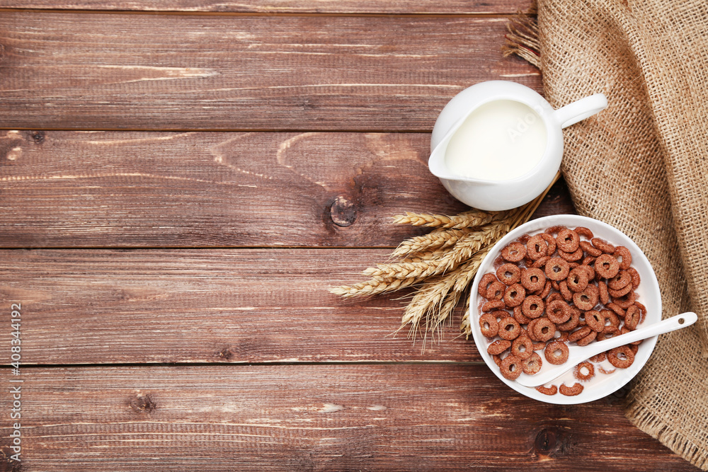Chocolate corn flakes in bowl with milk and wheat ears on wooden table Chocolate corn flakes in bowl with milk and wheat ears on wooden table