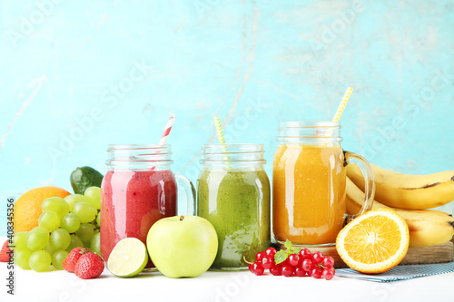 Fresh smoothies in glass jars with fruits and vegetables on wooden background