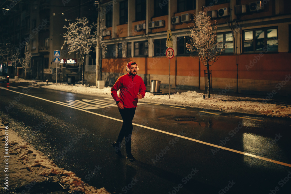 Man running on empty city street on winter night