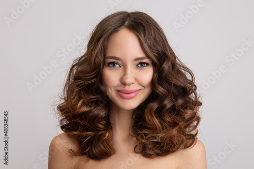Happy young beautiful woman with curly hair. grey background