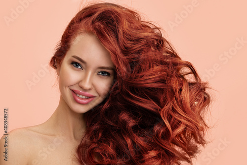 Beautiful smiling woman with luxurious curly red hair. Copycpase