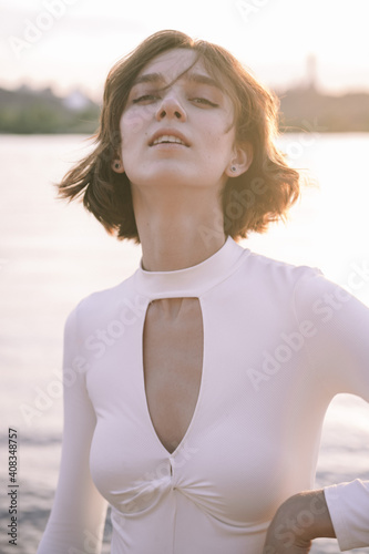 young woman posing and dancing near beach at sunset