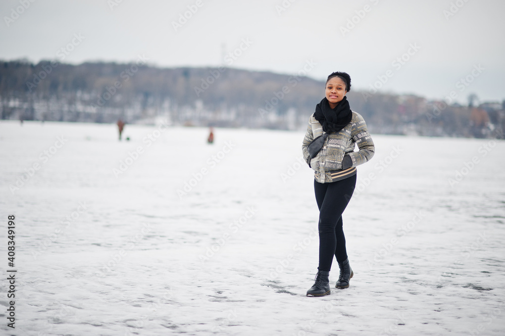 African woman wear in black scarf pose in frozen ice lake, winter day at Europe.