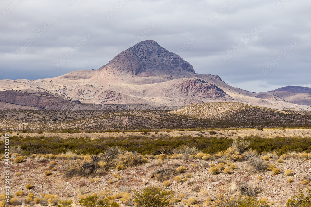 Close up of rolling hill mountain range behind vast desert vista landscape on cloudy day in rural New Mexico