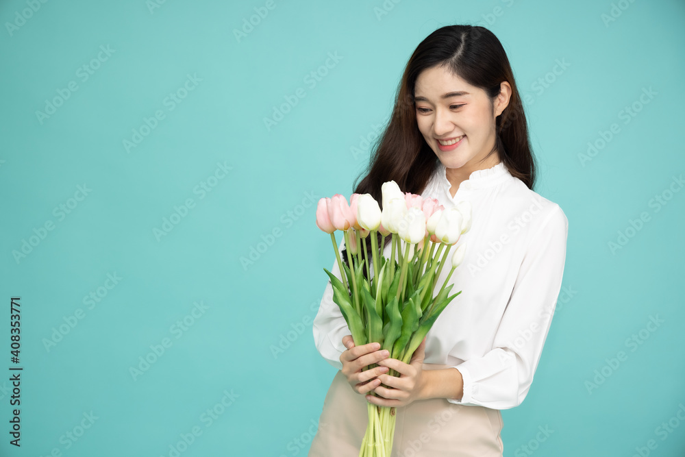Close up portrait of an attractive Asian woman holding tulip flower isolated over green background Close up portrait of an attractive Asian woman holding tulip flower isolated over green background
