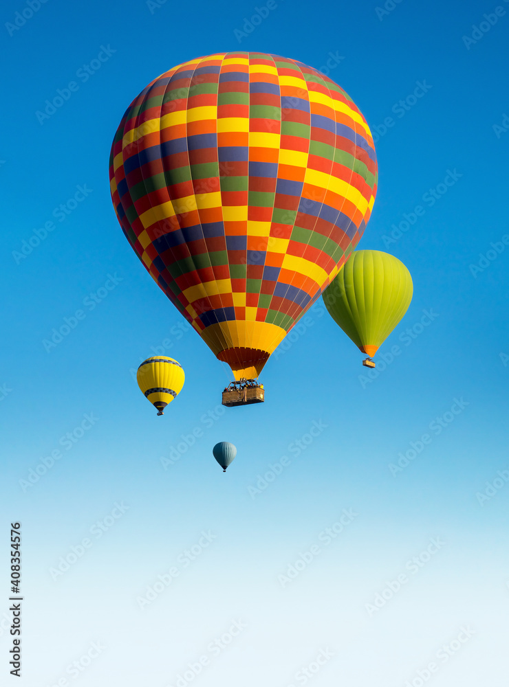Naklejka premium Colorful Hot Air Balloons for promotion of your travel agency or tour to Cappadocia, vertical landscape. Ballooning trip at clear blue sky background with copy space for text, bottom up view.