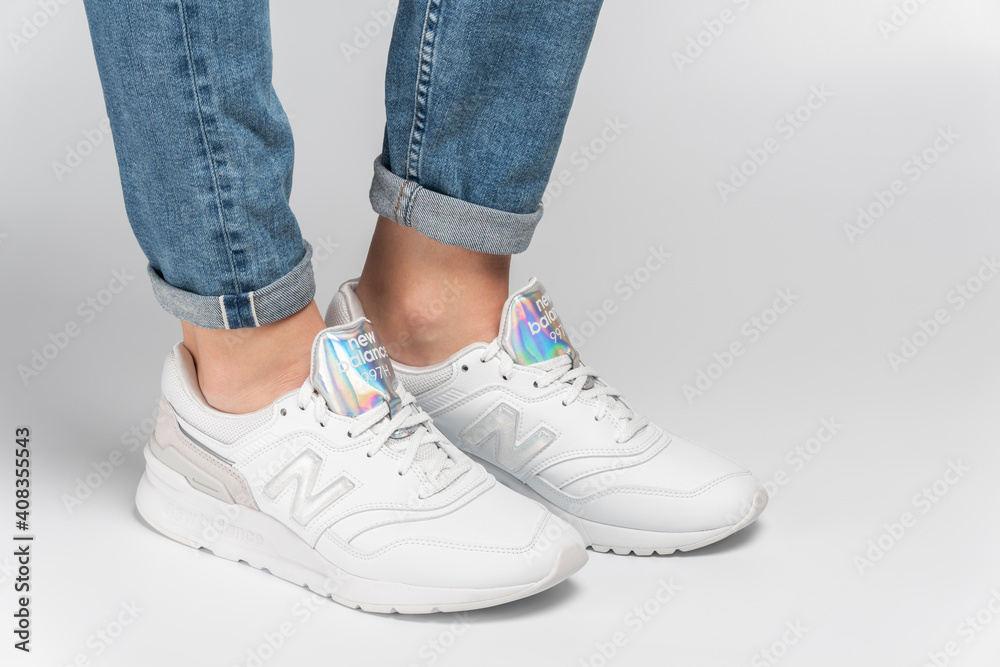 Kiev, Ukraine - January 03, 2021: White women's casual sneakers from New  Balance brand on a light background. Young girl in jeans and sneakers on a  gray background Stock Photo | Adobe Stock