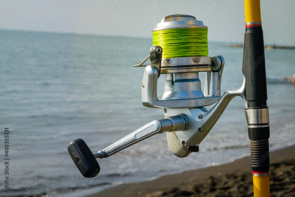Fishing rod, spinner, fish-rod, fishing pole close up detailed view. Grey  wavy seascape Stock Photo