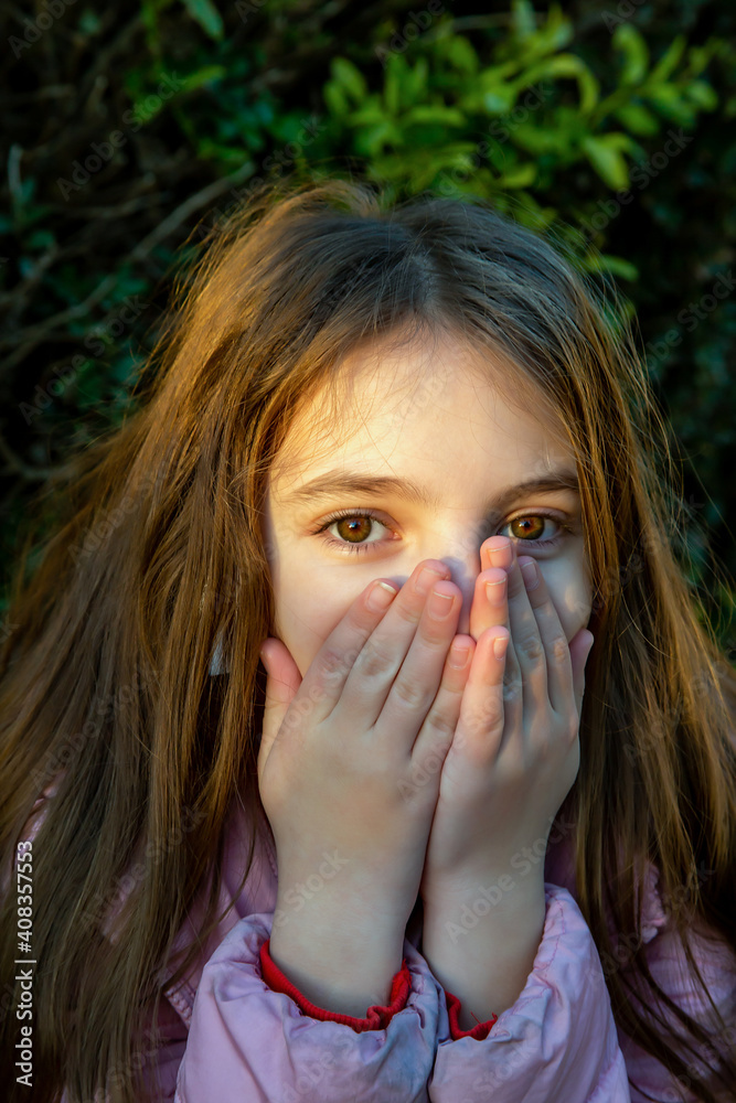 teenage girl with long hair holds her fingers in front of her mouth as if she wants to keep the whole secret teenage girl with long hair holds her fingers in front of her mouth as if she wants to keep the whole secret