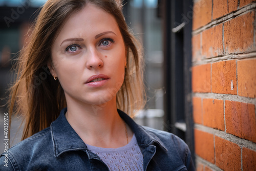 A beautiful, young and stylish woman poses in front of a camera near a brick wall. A large portrait © Андрей Иванов