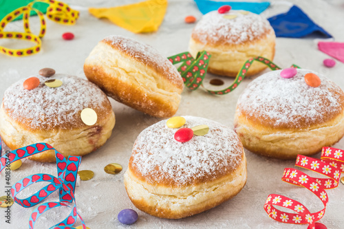 Krapfen, Berliner or donuts with streamers, confetti and chocolate beans on white background. Colorful carnival or birthday image.