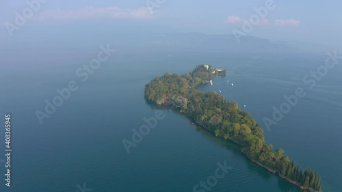 Fly in aerial shot revealing the vibrant Isola Del Garda in misty morning light photo