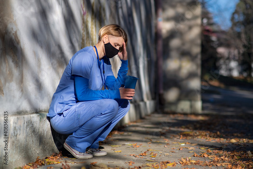 Worried woman caregiver or healthcare worker having a break outdoors, coronavirus concept. photo