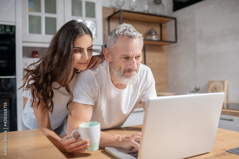 Woman hugging her husband while he is checking mails Woman hugging her husband while he is checking mails