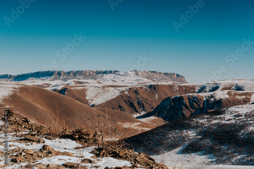 Landscape of winter snowy mountains and hills and blue sky. Sunny weather in the mountain. Mountain Caucasus Range. 