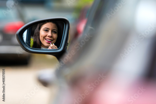 teenager driver applying lipstick using rear mirror in a car © ako-photography
