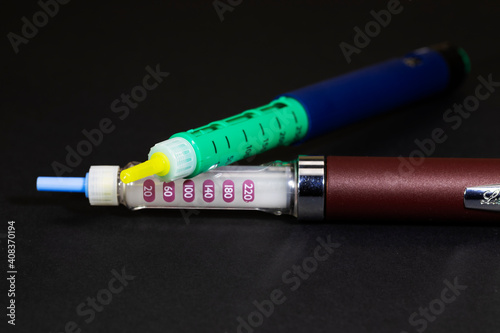two insulin syringe pens for hormone therapy of patients with diabetes mellitus, close-up, on a black background