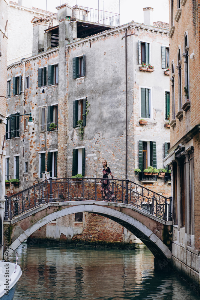 The girl walks through the narrow streets. A tourist travels around Venice.