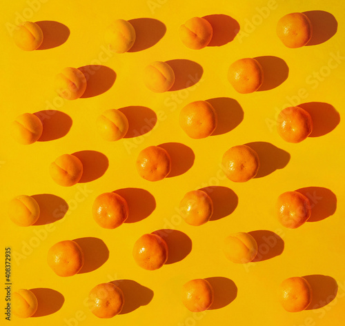 Flat lay pattern of fresh organic natural tangerines and apricots. Bright yellow background. photo