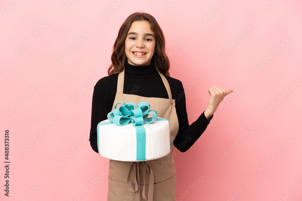 Little Pastry chef holding a big cake isolated on pink background pointing to the side to present a product Little Pastry chef holding a big cake isolated on pink background pointing to the side to present a product