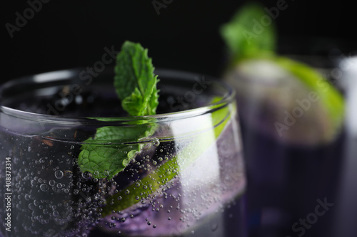 Delicious blackberry lemonade made with soda water on dark background, closeup