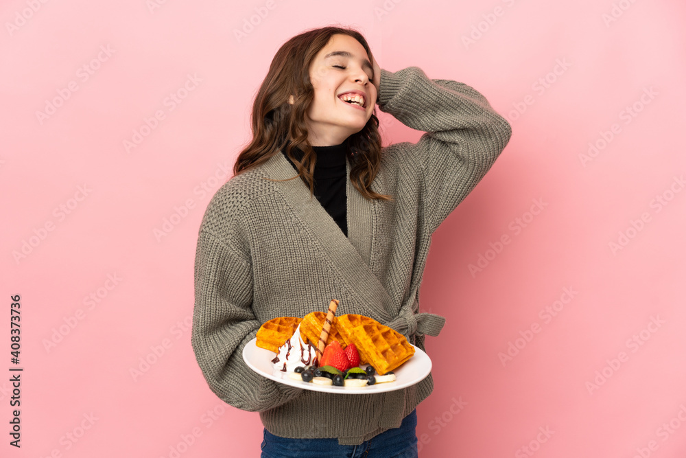 Little girl holding waffles isolated on pink background smiling a lot Little girl holding waffles isolated on pink background smiling a lot