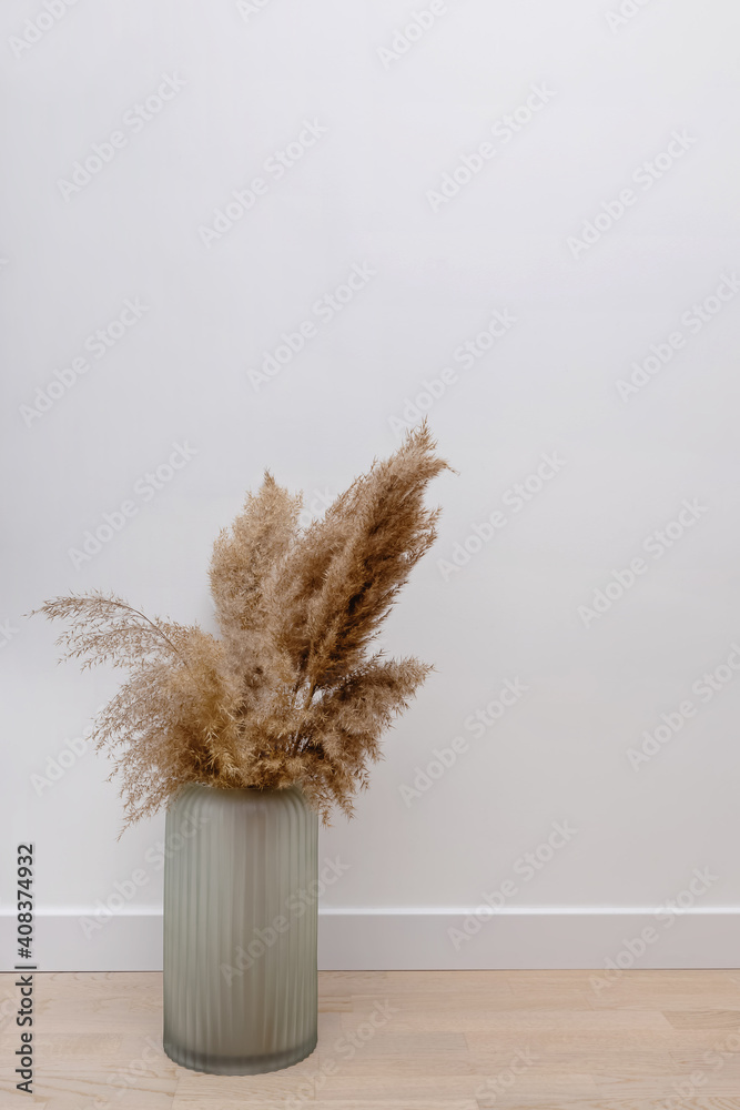 Plakat Pampas grass in opaque glass vase near white wall.