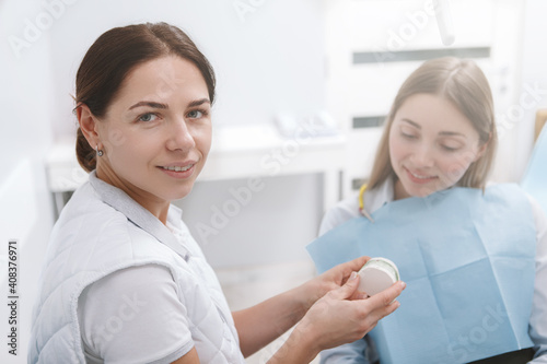 Young female dentist smiling to the camera while working with a patient