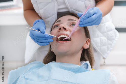 Young woman getting dental treatment by professional dentist at the clinic