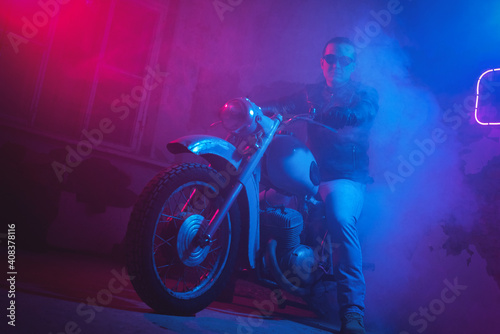 Motor biker in the neon lights in the old garage.