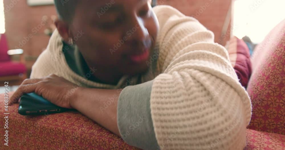 Close up on a young man taking a nap on a couch, getting woken up by an alert on his phone. Close up on a young man taking a nap on a couch, getting woken up by an alert on his phone.