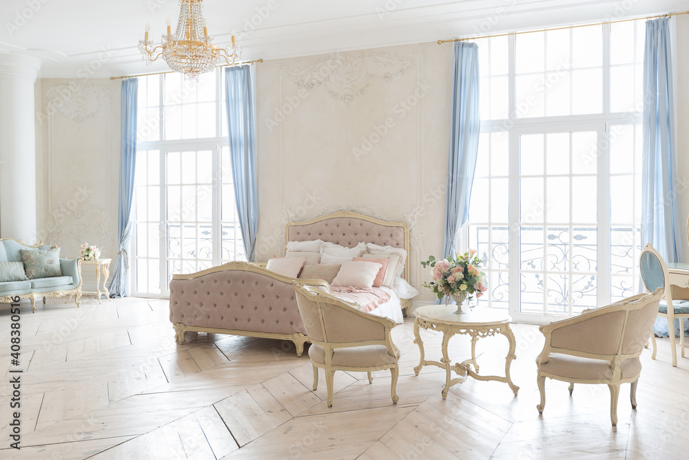 Fototapeta premium luxurious light interior in the Baroque style. A spacious room with a road chic beautiful furniture, a fireplace and flowers. plant stucco on the walls and light wood parquet