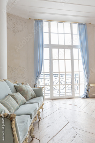Fototapeta Naklejka Na Ścianę i Meble -  luxurious light interior in the Baroque style. A spacious room with a road chic beautiful furniture, a fireplace and flowers. plant stucco on the walls and light wood parquet