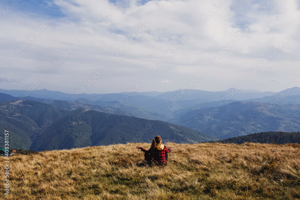 Woman sitting in meditation pose looking to the mountain peaks