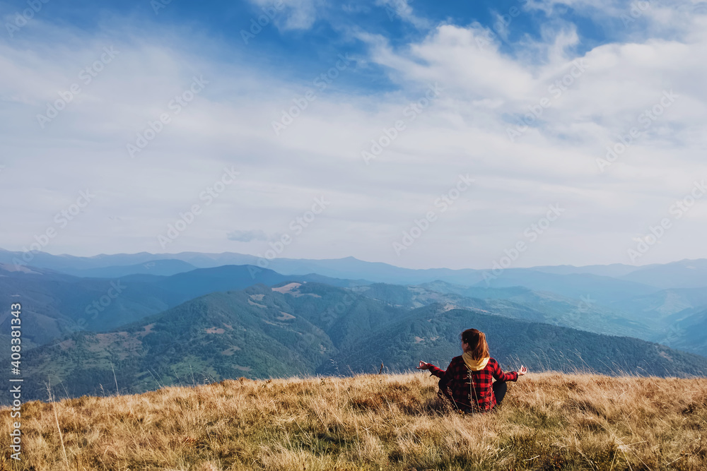 Woman sitting in meditation pose looking to the mountain peaks