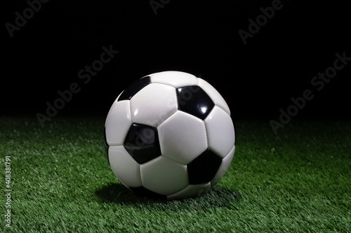 Traditional black and white soccer ball on green field with dark background © Daniel Thornberg