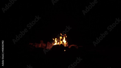 Small camp fire burning in ring of stones isolated in black
