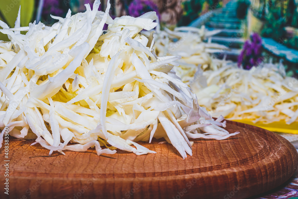 Sliced vegetables for cooking. Vegetables on a round wooden cutting board lying on the kitchen table. Sliced cabbage. Sliced vegetables for cooking. Vegetables on a round wooden cutting board lying on the kitchen table. Sliced cabbage.